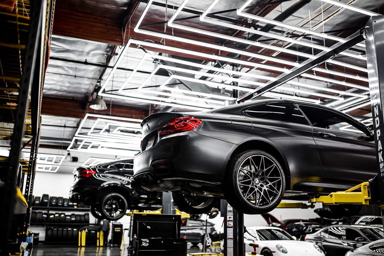A real Shop repair bay, cars on lifts under bright shop lighting