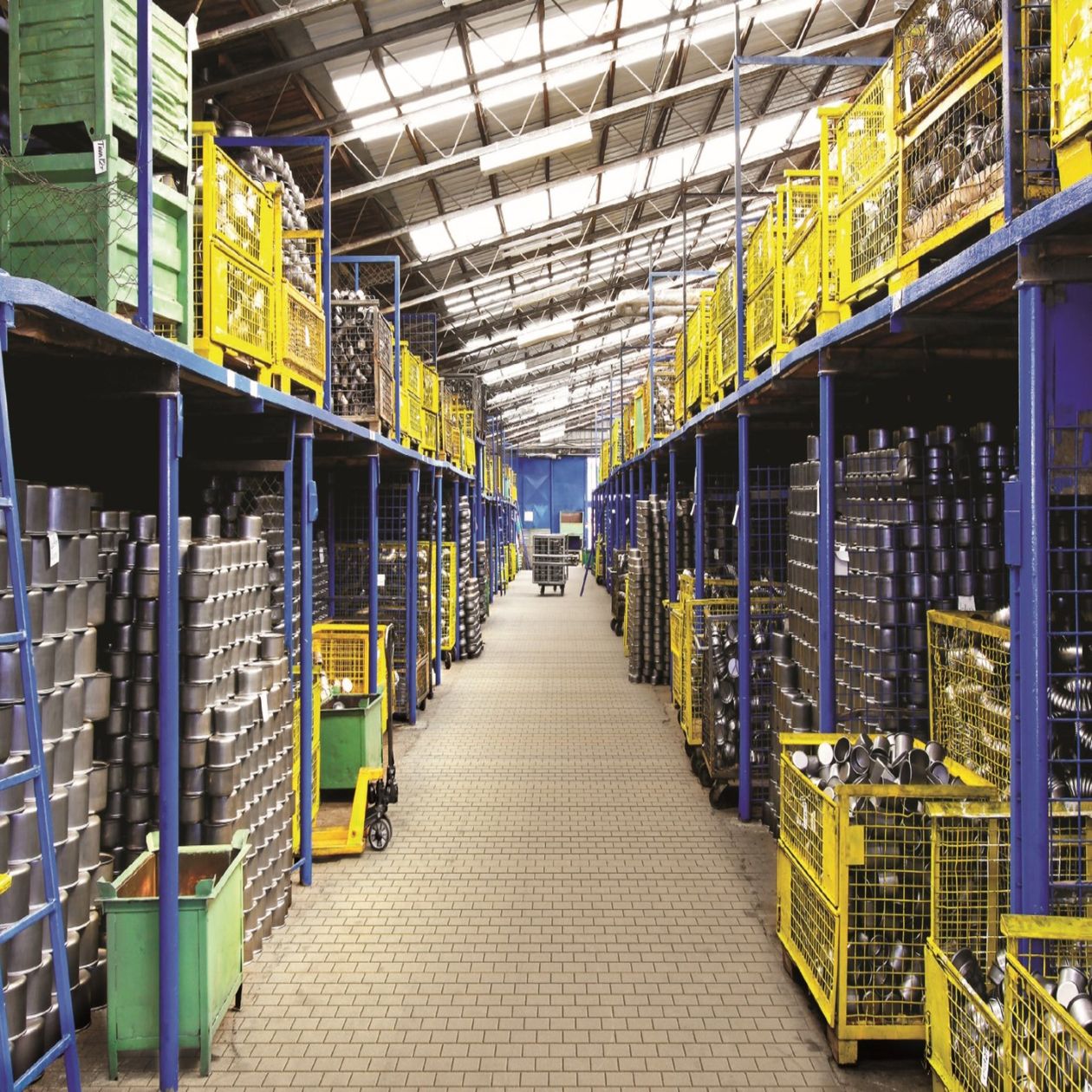 A real parts warehouse aisle, shelving stacked with automotive parts